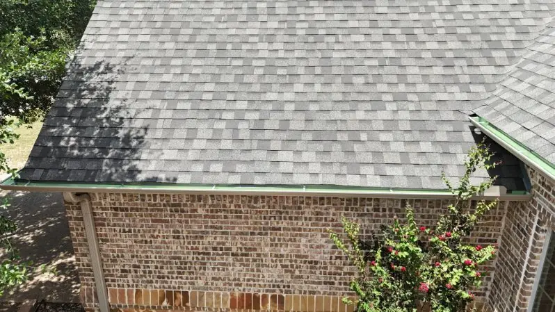 An ACS fitter on a ladder working on the gutter line of a brick house