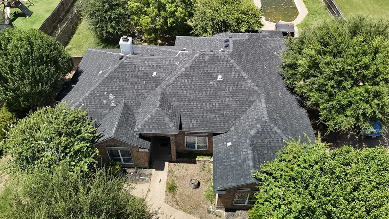 Finished shingle roof on a home among trees, from above